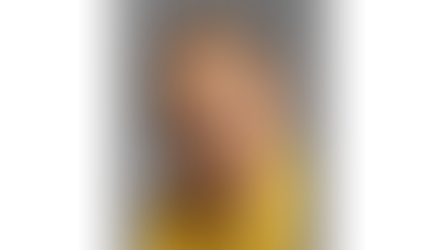 James Jim lewis Besaw in a bright yellow shirt against a gray background, looking calm and composed.