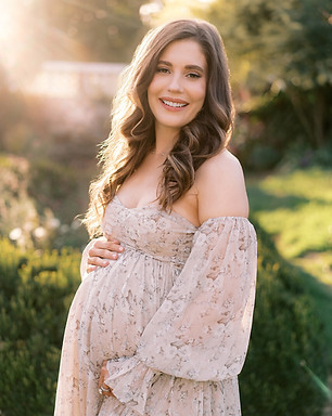 Expectant mother wearing soft natural makeup and loose waves for a maternity portrait session