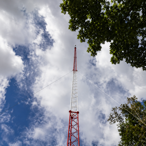 Tall red and white communication tower against a cloudy sky