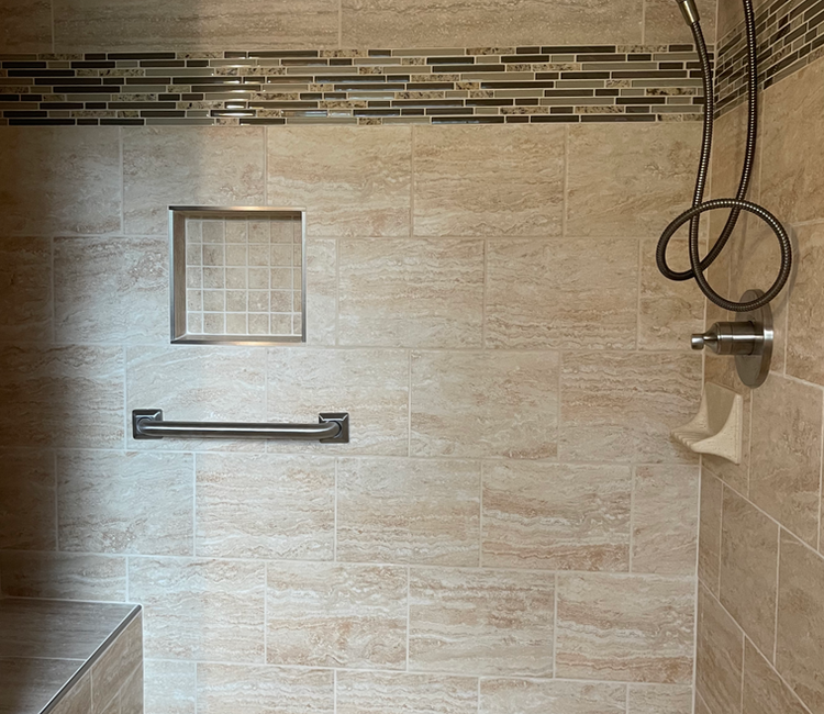Shower tile installation in Chattanooga, TN with grab bar, recessed niche, bench seating, and custom wall tile.