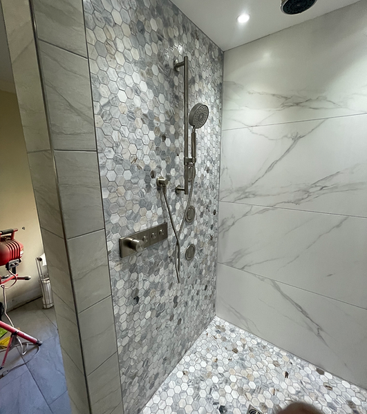 Modern custom tile shower with mosaic accent wall and large-format marble-look tile