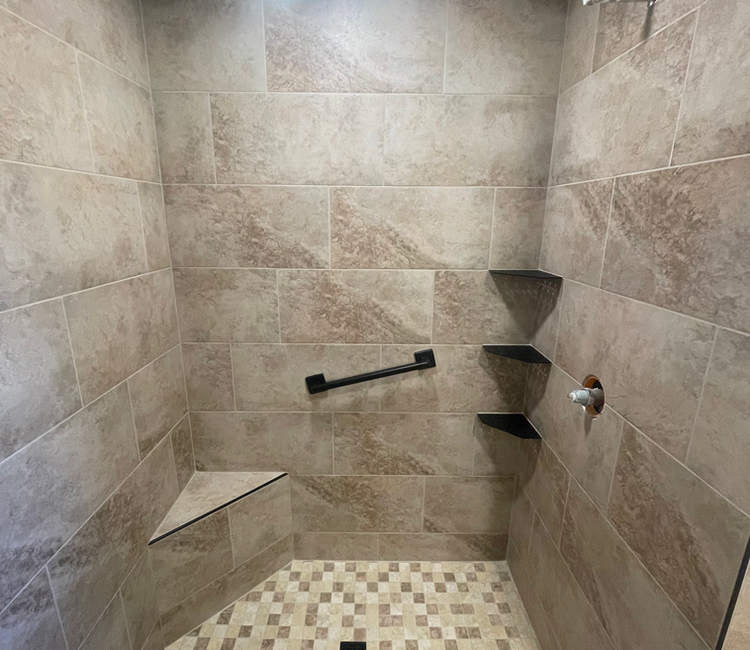 Shower tile installation in Chattanooga, TN with bench, grab bar, corner shelves, and mosaic shower floor.