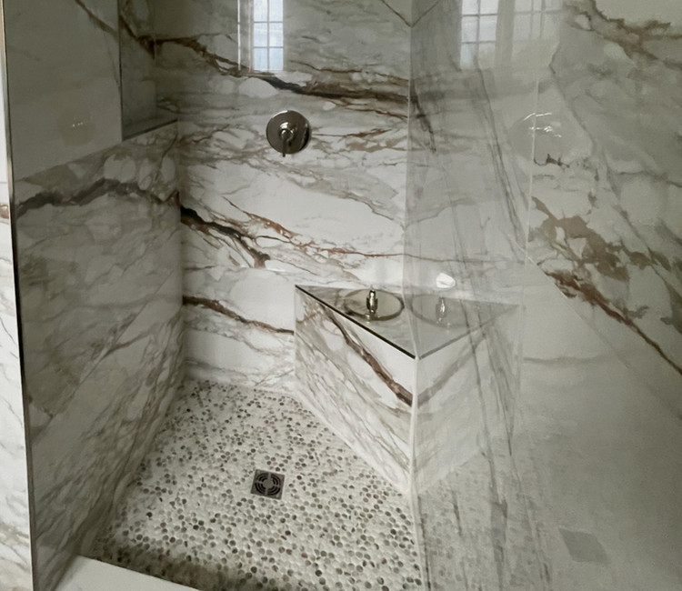Shower tile installer in Chattanooga, TN with marble-look wall tile, built-in bench, and custom shower layout.