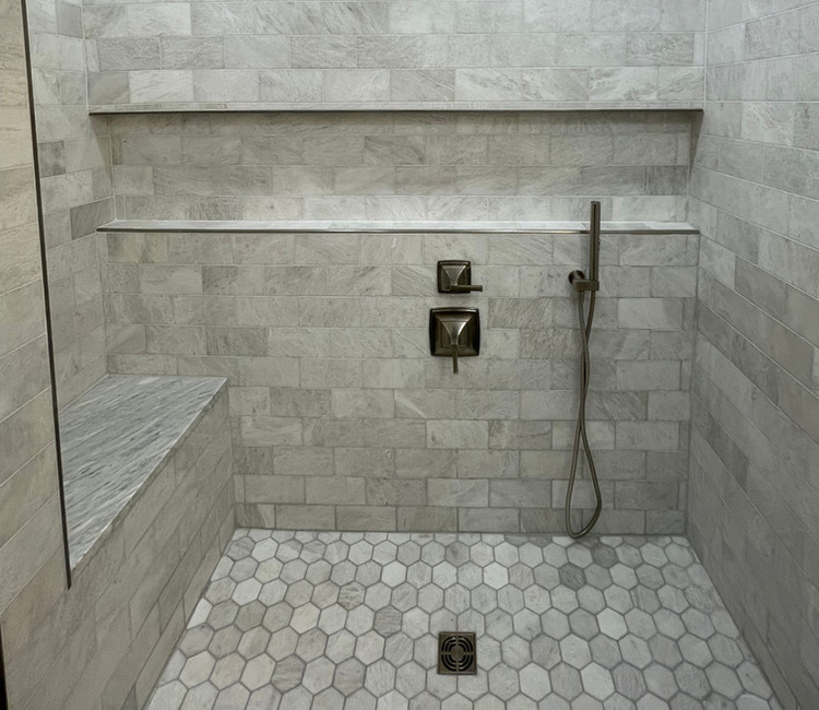 Custom shower tile work in Chattanooga, TN with built-in bench, niche shelf, and large format wall tile.