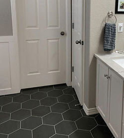 Bathroom tile floor installation featuring large black hexagonal tiles, paired with a white vanity and marble countertop, completed by Chattanooga Tile Company in Chattanooga, Tennessee.
