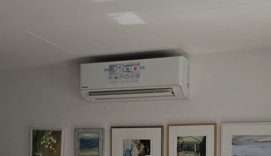 Panasonic luft luft värmepump innedel monterad ovanför vägg i vardagsrum.