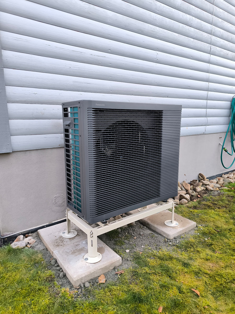 Mörkgrå luft-vattenvärmepump installerad utomhus på markstativ vid vit träfasad. Modern och energieffektiv uppvärmningslösning för villa med fokus på lägre elförbrukning.