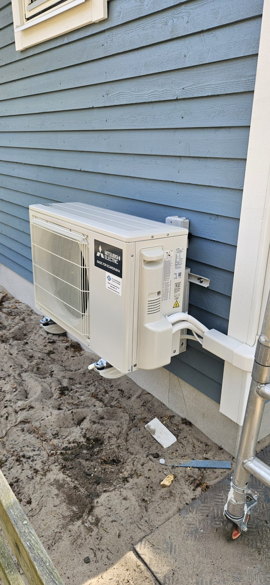 Mitsubishi Electric luft-luftvärmepump monterad på väggkonsoler utanför villa i Kristianstad. Diskret installation med kabelkanal och rördragning längs fasaden för effektiv uppvärmning och energibesparing året runt.