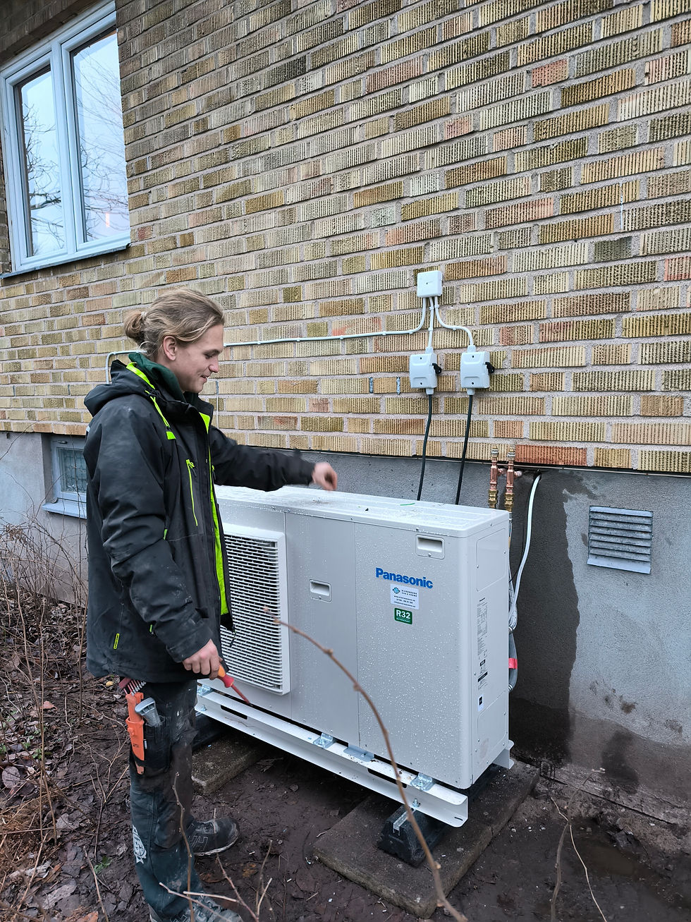Tekniker från Siverssons VVS installerar en Panasonic luft-vattenvärmepump utomhus vid tegelhus. Värmepumpen är monterad på markstativ och ansluten för energieffektiv uppvärmning av villan.