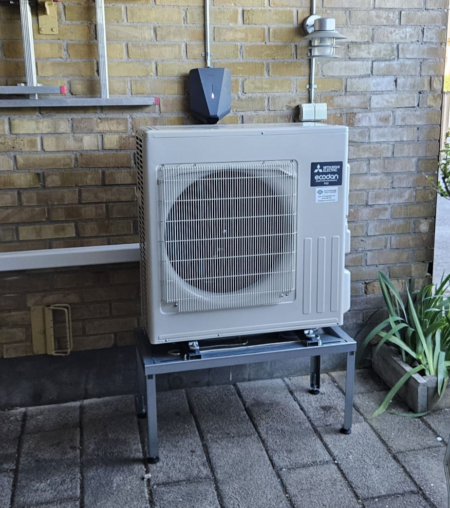 Professionell installation av Mitsubishi Ecodan luft-vattenvärmepump i Kristianstad. Modern värmepumpslösning monterad på stativ vid villa för lägre energikostnader och hög komfort.