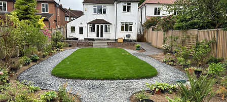 Complete rear garden transformation with circular lawn framed by gravel and well-kept planting beds.