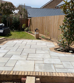 Light grey patio slabs being fitted to create a modern outdoor living space with brick edging