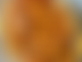 Crispelle di riso catanesi (sfinci) appena fritte, dorate e cilindriche, disposte su un piatto e ricoperte con colata calda di miele e arancia, spolverate di zucchero a velo e cannella.