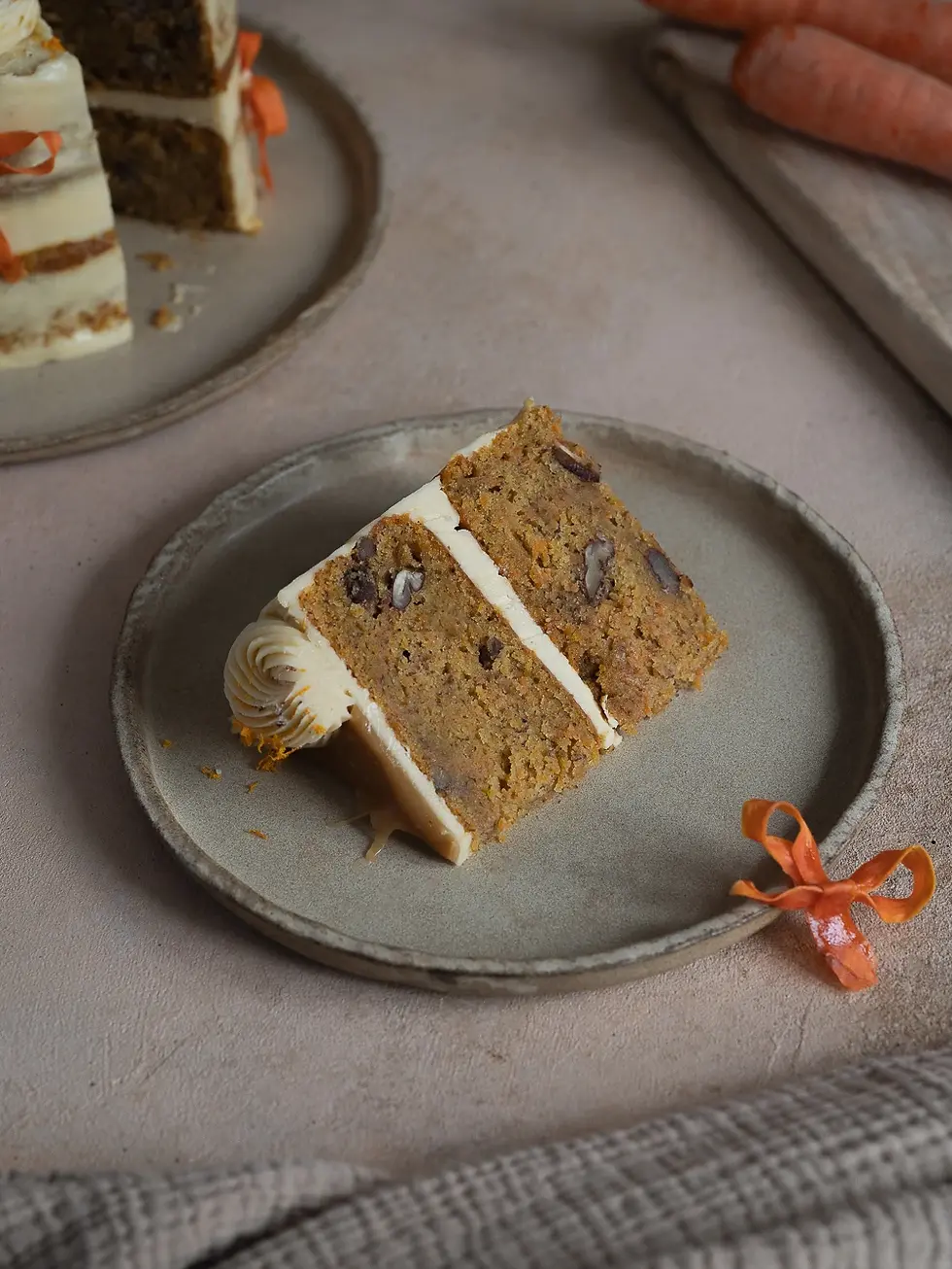 Carrot Layer Cake mit cremigem Frischkäse-Frosting, getoppt mit Salzkaramell und verziert mit feinen Karotten-Schleifen
