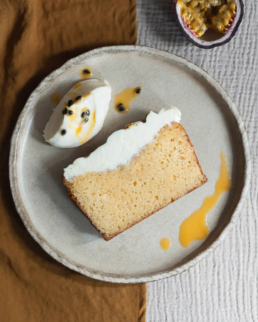 Ein Stück Maracuja Kastenkuchen mit schöner Textur und Frischkäse Frosting on top. 
