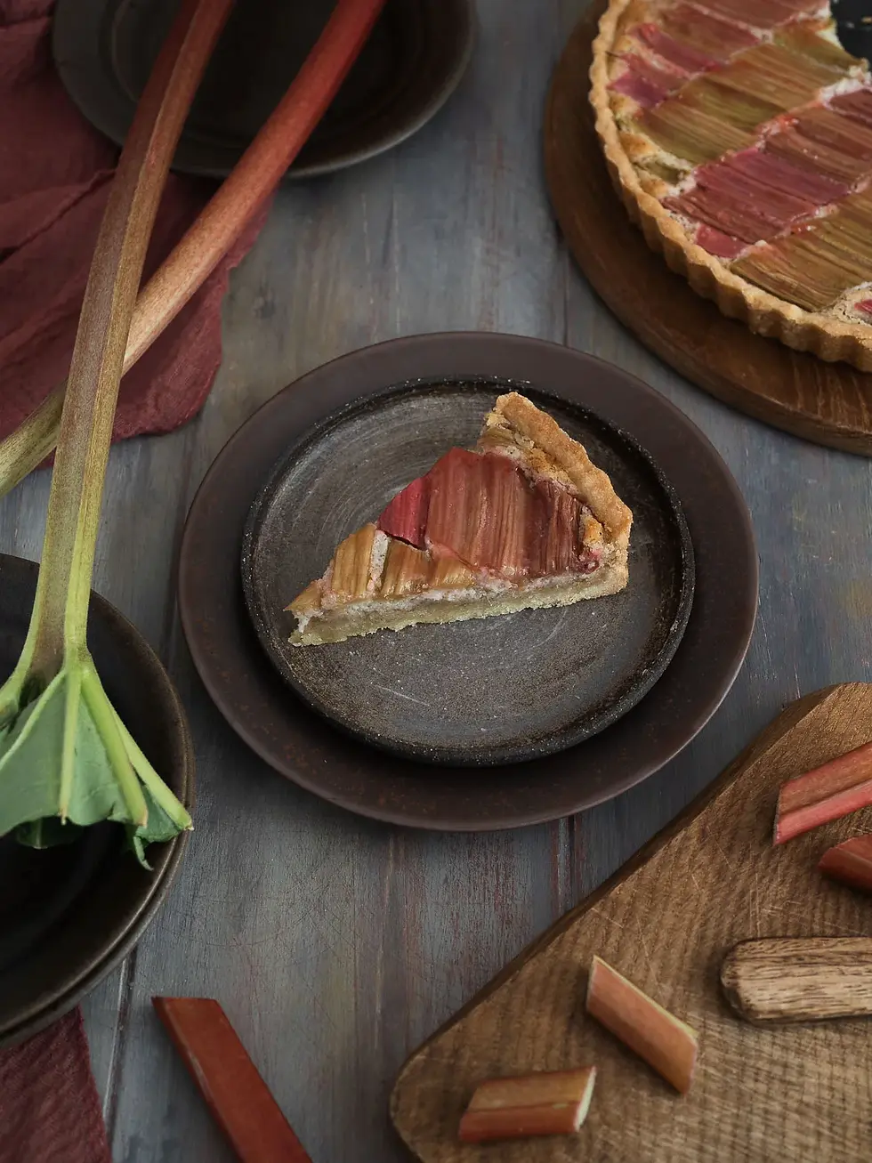 Vegane Rhabarber Frangipane Tarte in einer flachen Tarteform mit goldbraunem, mürbem Boden. Auf der saftigen Mandel-Frangipane liegen rosa-grüne Rhabarberstücke dekorativ angeordnet. Die frühlingshafte Tarte wirkt außen knusprig und innen weich und saftig.
