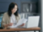 A person calmly organising paperwork at a table with a laptop, warm natural light, hopeful rather than anxious.