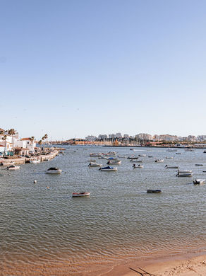 The estuary at Ferragudo in the western Algarve on a clear morning, with the whitewashed town on the left, small fishing and leisure boats moored on the water, and Portimao across the far side.
