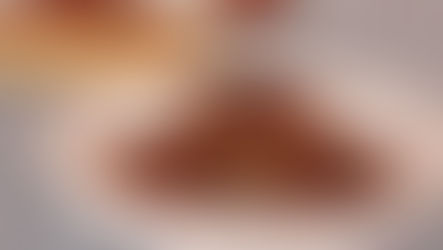 Three lentil sausage patties in a white casserole dish with maple syrup being poured over them