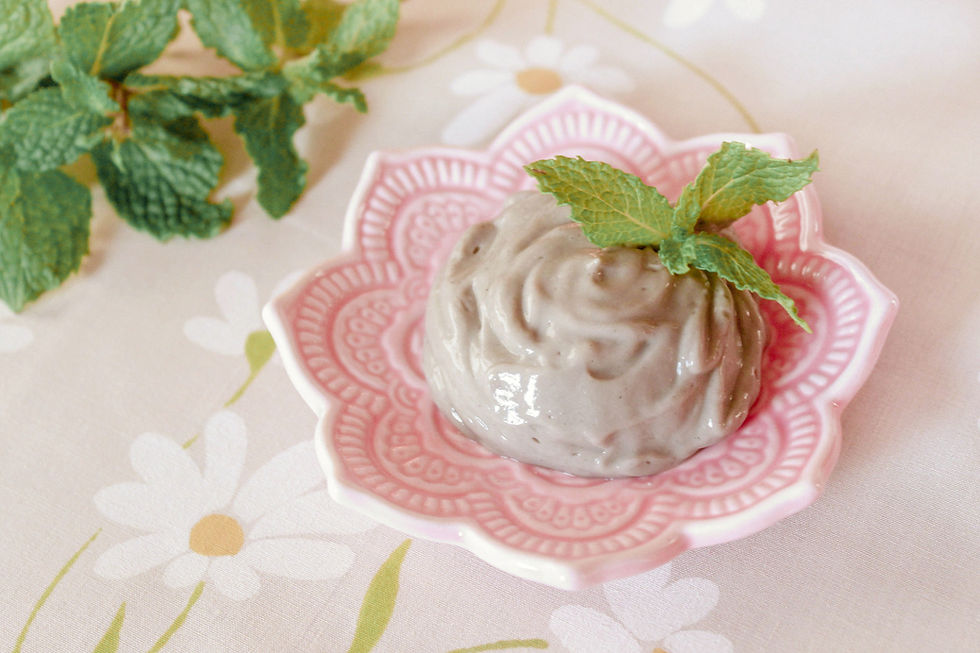 A pink dish with all-natural clay toothpaste and a sprig of fresh peppermint leaves