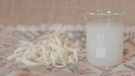 A small glass container of diy laundry soap with a pile of soap shavings