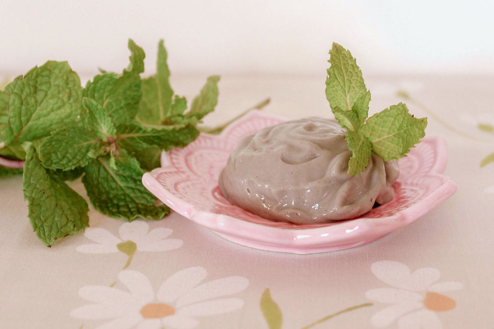 A pink dish with all-natural toothpaste on it, surrounded by fresh mint leaves