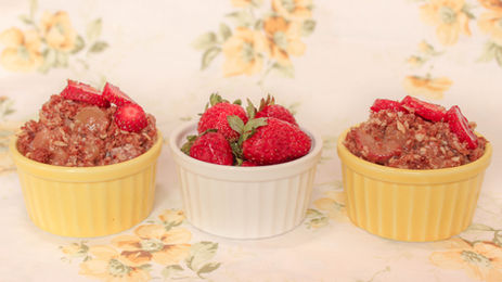 Two dishes of organic strawberry rhubarb crisp and one dish of organic strawberries