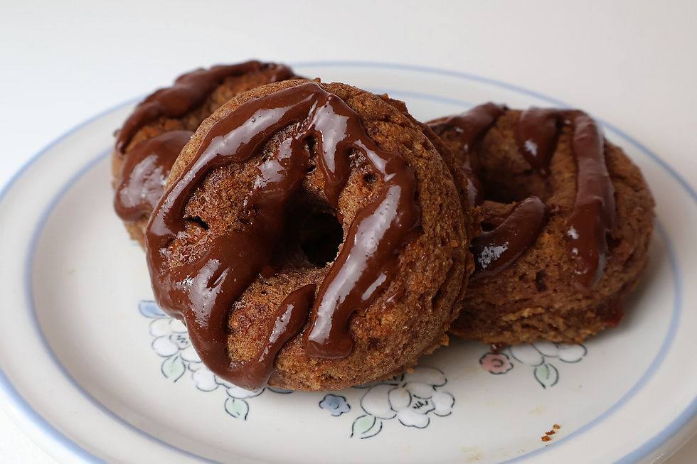 Three apple cinnamon glazed donuts on a floral plate, close-up on a white background.