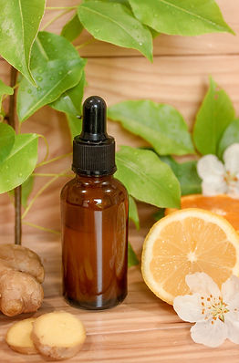 A brown glass bottle of body oil with slices of fruit and leaves