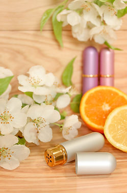 Three aromatherapy inhalers surrounded by white flowers and slices of oranges and lemons