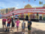 Children enjoying a sunny day while exploring the vibrant streets of Ponce, Puerto Rico, with colorful murals and festive decorations in the background.