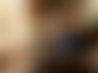 Man in a cozy room, typing on a laptop in an armchair. Sunlit window, bookshelves, plants. Swirling light trails create a magical mood.