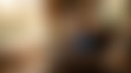 Man in a cozy room, typing on a laptop in an armchair. Sunlit window, bookshelves, plants. Swirling light trails create a magical mood.