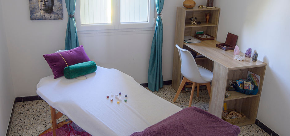 Amanda Cox's Reiki Room, with treatment table with chakra crystals around a selenite wand in the centre as well as the desk and decor