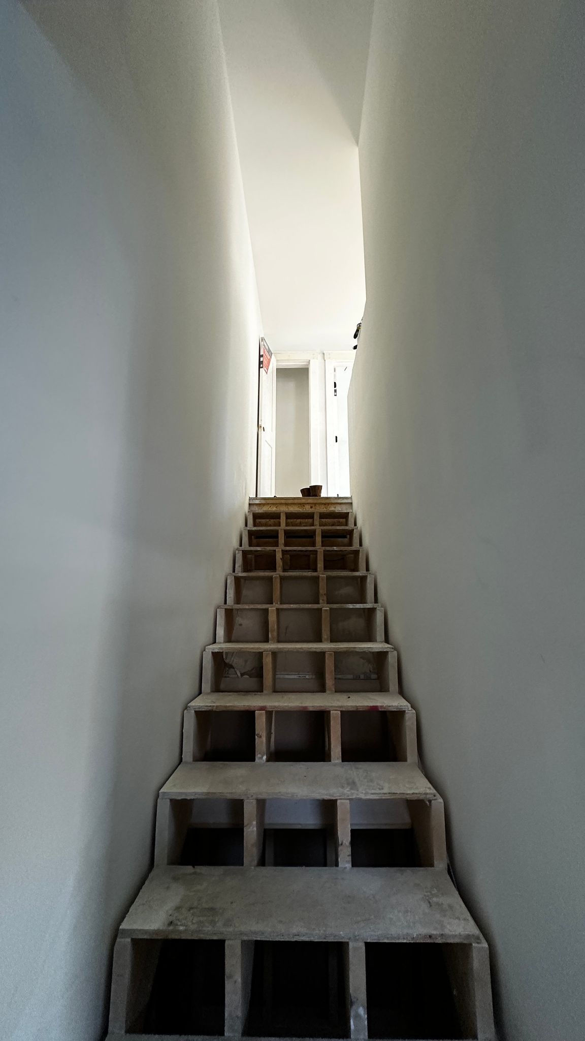 Narrow staircase leading to a bright doorway.