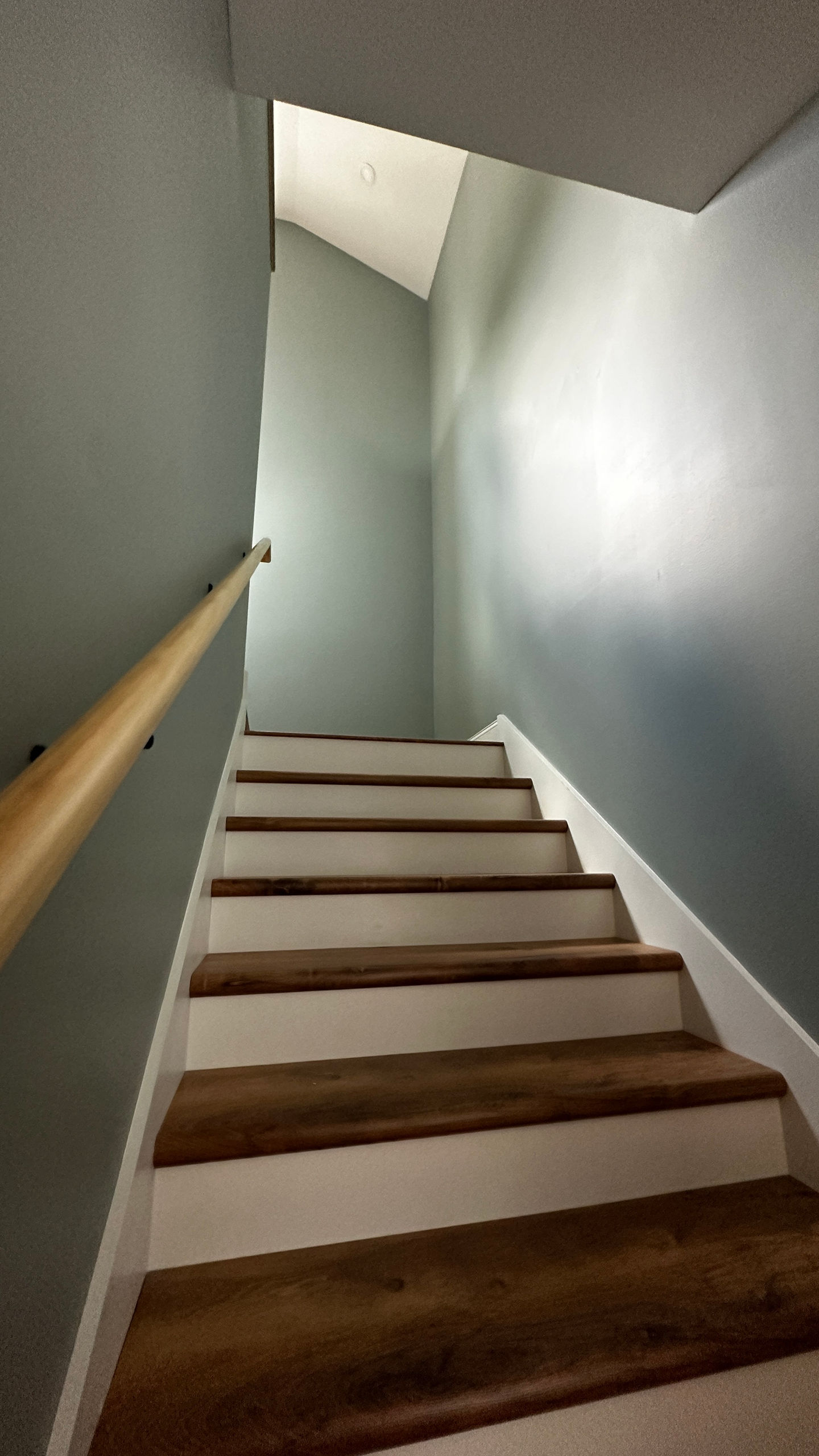 Narrow staircase with wooden steps and railing.