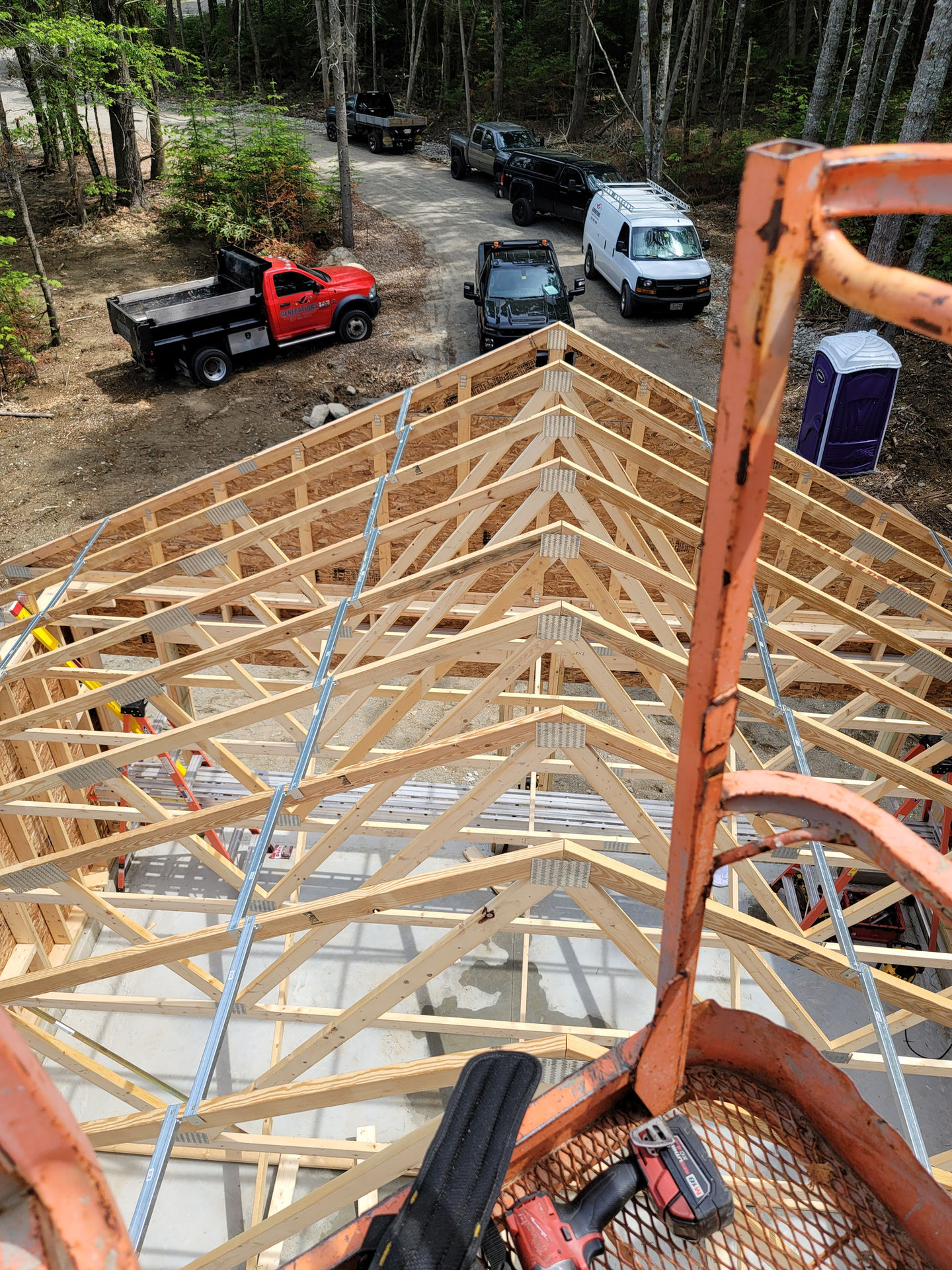 Construction site with wooden roof trusses visible.