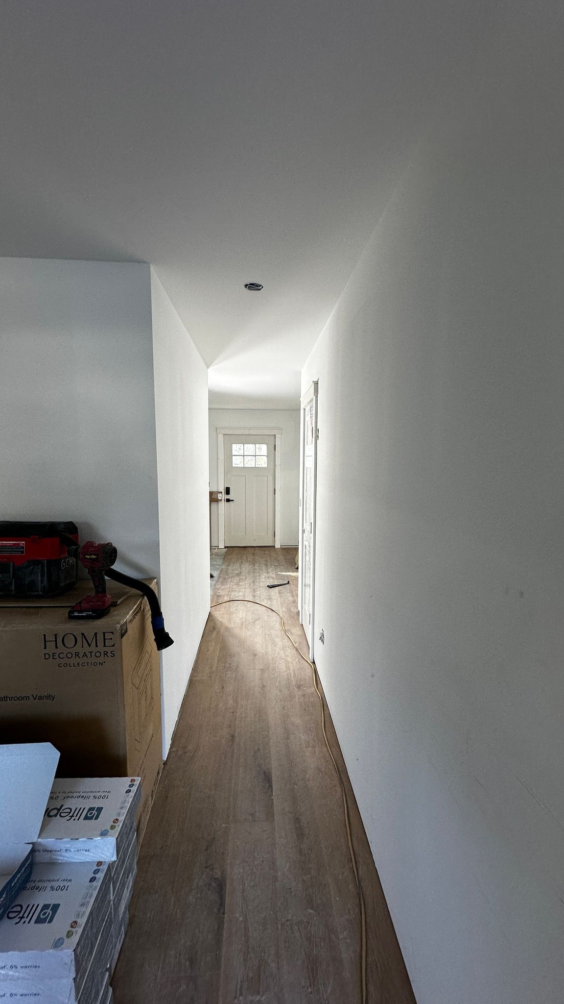 Narrow hallway with wooden floor and white walls.