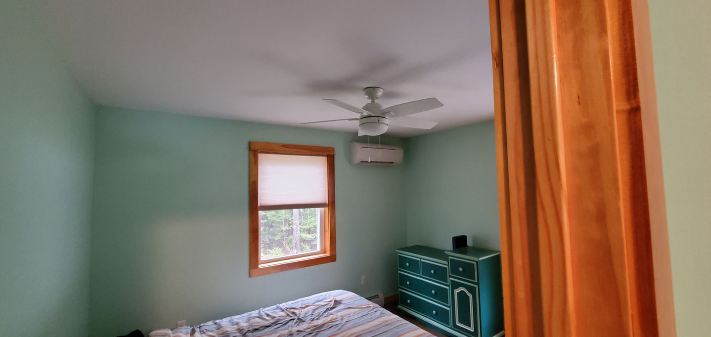 Small bedroom with teal dresser and ceiling fan.