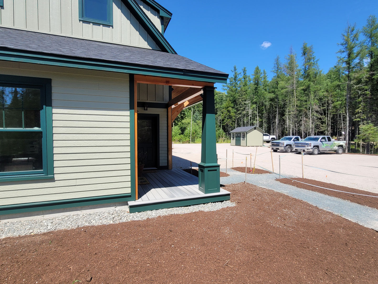 House exterior with green trim and forest background.