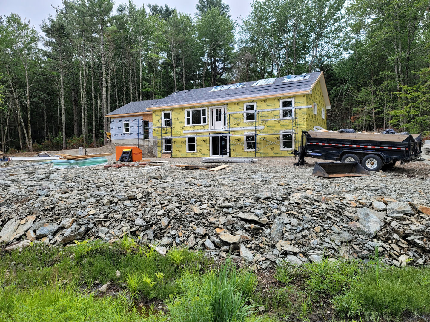 House under construction surrounded by trees and rubble.