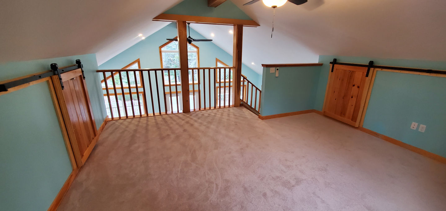 Carpeted room with wooden railing and blue walls.