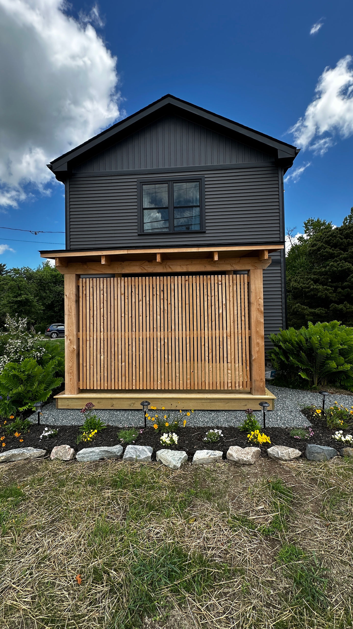 Wooden structure with plants and stones in front.