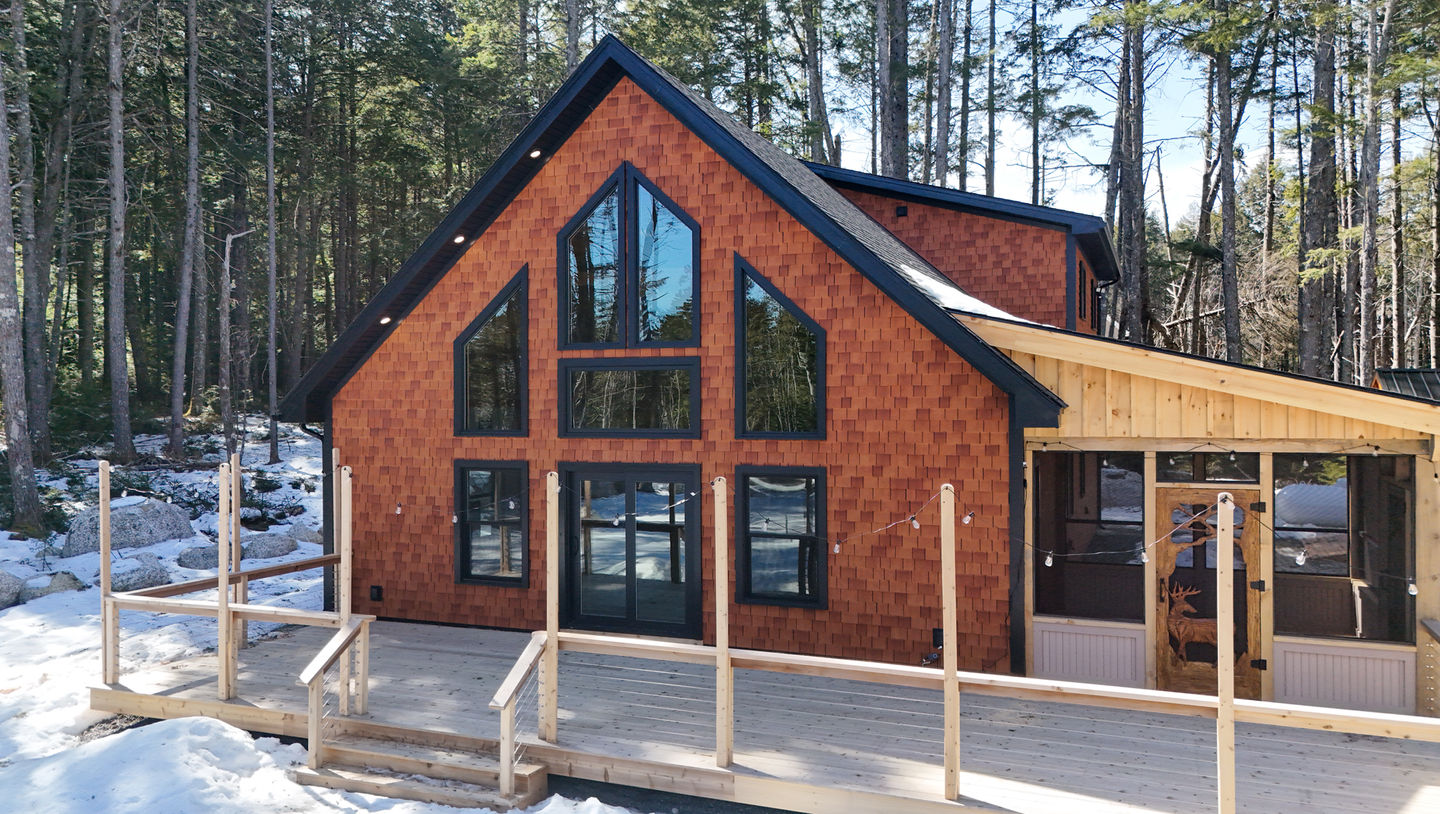 A-frame house with large windows in wooded area.