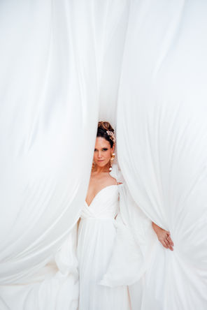Bride in white dress posing in draped white fabric at The Santa Marina Mykonos