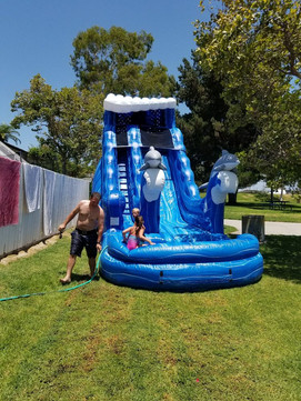 Family enjoying the 22' Tall Dolphin Pool Water Slide setup in a small backyard for summer fun in Santa Ana, California by Gold Star Jumpers