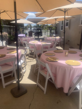 At home graduation party setup with tables, chairs, umbrellas, and table linens from Gold Star Jumpers, in Garden Grove, California.