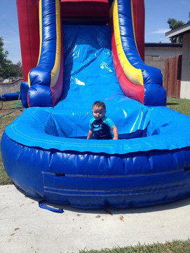 Toddler enjoying the 5 - 1 Combo Bounce House rental from Gold Star Jumpers in the summer sun, in Anaheim, Orange County, California.