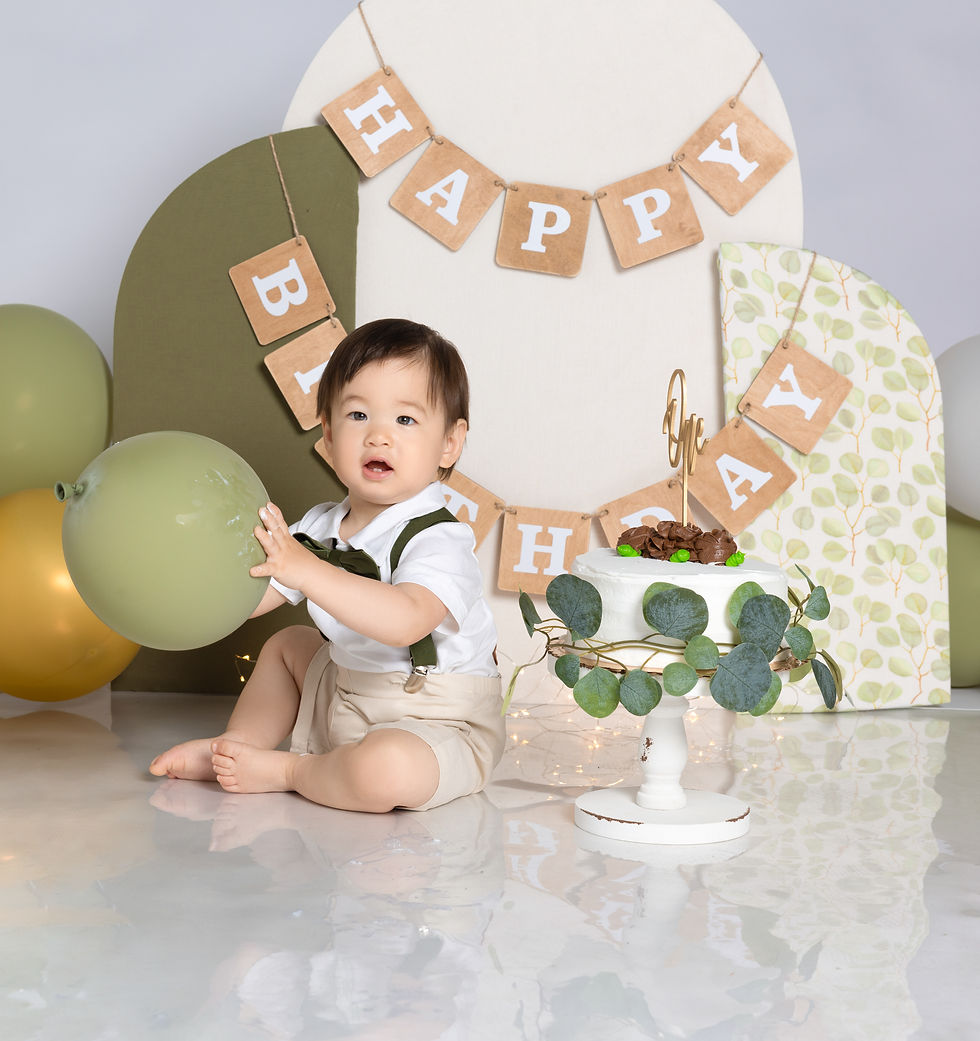 One-year-old boy holding green balloon during cake smash session in San Diego.