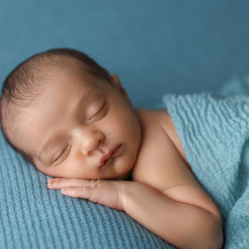 Newborn baby boy sleeping on blue background with blue wrap, photographed by San Diego newborn and baby photographer.